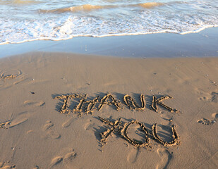 text THANK YOU written on the sand by the sea