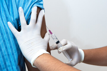 Doctor giving vaccine injection into female shoulder.