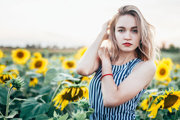 A young girl in a shirt stands in sunflowers