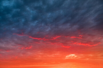 Colorful and dramatic sunset with red tinted clouds. Sky Background or texture