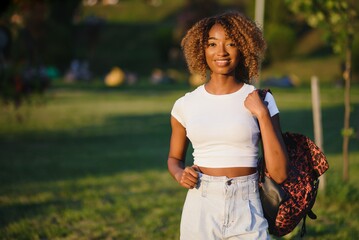 Close up beauty outdoor portrait of attractive charming young african-american smiling woman with natural make up and afro hair, enjoying a day at the park. Outdoor portrait of African girl