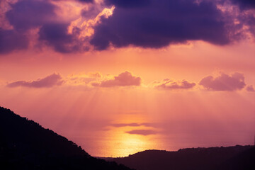 Stunning sunset over the Mediterranean Sea in Lebanon. Bright backlit sky and clouds. Silhouettes of mountains in the rays of the sun. Incredible wallpaper