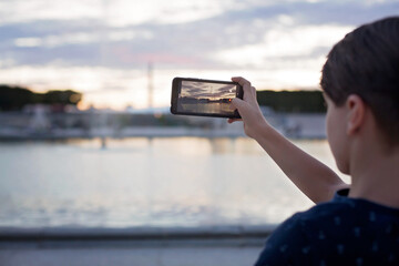 Child, taking picture with phone of a fountain in Paris