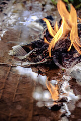 Burning newspaper flames reflected on a water puddle with tyre tracks