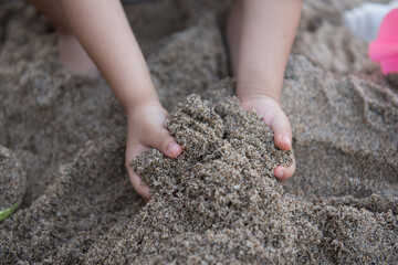 Close up hand of little girl playing on the sand