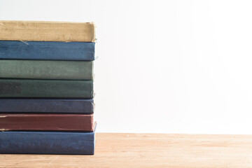 A big stack of old, faded, multicolored, yellowed books on a light background. Minimal style, copy space, side view