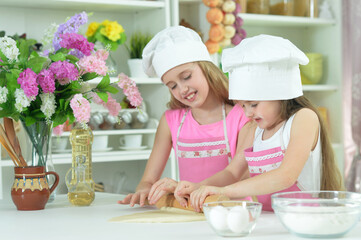 Cute little girls in hats making dough