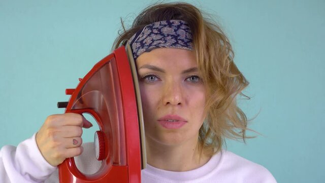 Portrait of a Beautiful and Attractive Woman in a Black Bandana and Curly Hair Ironing Her Face. Serious Facial Expression. Stylish Video Filmed In The Studio.