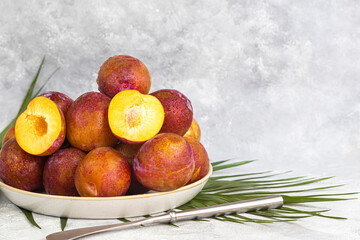Fresh plums are yellow-red. Juicy and large. Purchase of goods for future use. Vitamins for immunity. On a light background.