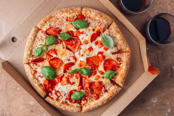 Pizza box delivery concept. Open box with hot tasty italian sliced pepperoni pizza with basil.