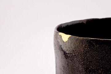 Japanese kintsugi black raku ceramic chawan, restored with real gold. Antique pottery kintsukuroi.