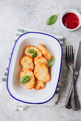 Hash brown or potato pancakes on plate with catsup on light gray background