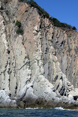 Fototapeta na wymiar Scogliera di rocce verticali con mare e frangenti