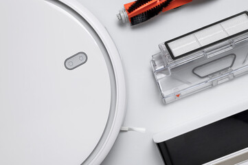 Modern robot vacuum cleaner, filter, brush on gray background flat lay. New technologies, quick house cleaning, automatic robot assistant. Future technology, smart appliance for cleaning house