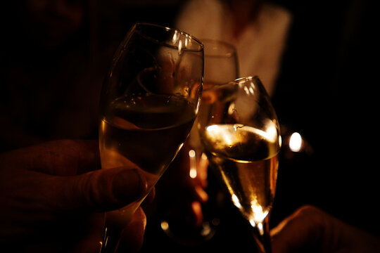 Anstossen mit drei Champagnergläser, Wein oder Sekt im Kerzenlicht