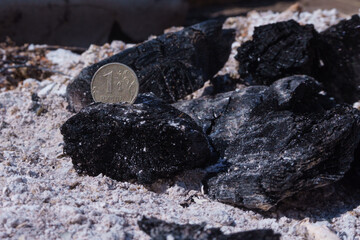 Russian coin lie on black hot coal among the ashes. One rubles in fire. Russian currency devaluated, finance and business concept
