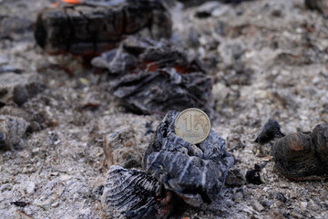 Russian coin lie on black hot coal among the ashes. One rubles in fire. Russian currency devaluated, finance and business concept