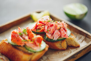 Toasts with fresh cucumber and smoked salmon served with lime shavings