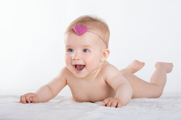 healthy cute baby lies on white bed,  smile on his face