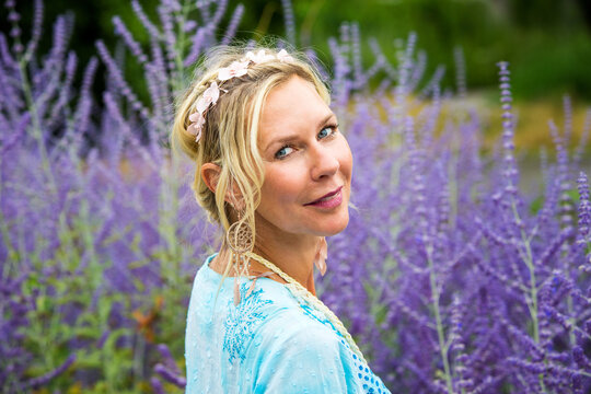 Blond Woman In Her 40s Standing In A Field Of Purple Flowers