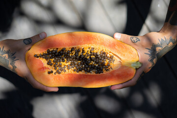 tropical fruits, papaya in hands with tattoos.