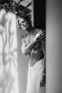 handsome young man in tattoos in the bathroom after a shower in a towel. lifestyle concept.