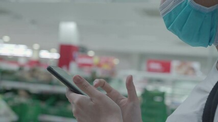 Close up woman wear protective mask using smartphone standing inside the mall supermarket, paying bills through phone 4g 5g technology, promtpay service, virus pandemic, shopping at grocery - Powered by Adobe