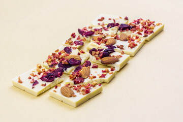 A broken bar of white chocolate with dried berries, candied fruits and almonds.