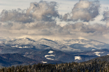 Fototapeta na wymiar mountains in winter peaks forest-covered clouds in the sky