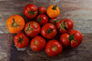 Abundance ripe organic tomatoes on dark rustic background. Colorful tomatoes 
