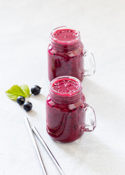 Berry drink, black currant smoothie in a jar with a metal straw on a light background