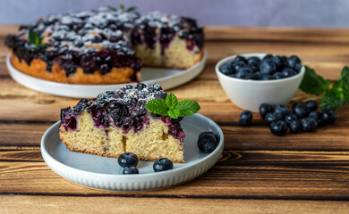 Selective focus. Piece of homemade blueberry pie on the plate with berries and fresh baked pie on the back