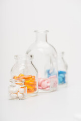 selective focus of pills in glass bottles on white background