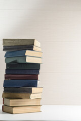 A big stack of old, faded, multicolored, yellowed books on a light background. Minimal style, copy space, side view