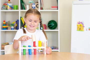 little girl hammers the sticks with a hammer. development of hands and fingers. development of fine motor skills