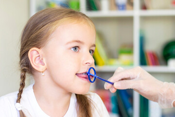 Speech therapy massage of the girl's tongue. a speech therapist makes a tongue massage to a child with a staging probe.