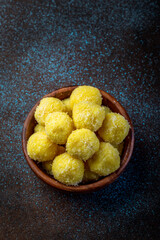 saffron flavoured desiccated coconut ladoo in a wooden bowl