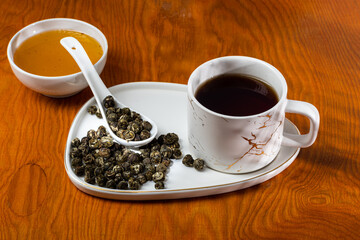 loose tea into the saucer next to the cup and sweets on the wooden background with different lighting