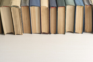 A row of old, faded, multicolored, yellowed books on a light background. Minimal style, copy space, side view