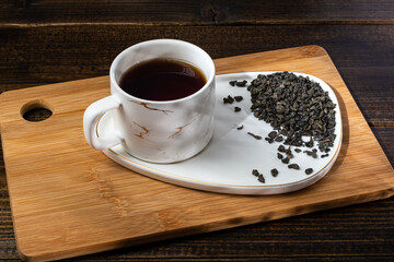 loose tea in a saucer next to a mug on a wooden background with different lighting