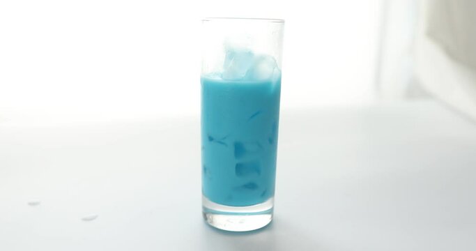 Pouring espresso coffee in glass cup with curacao syrup and milk to make blue latte
