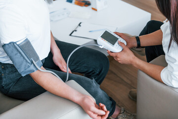 Obraz premium Measuring blood pressure. Young woman have a visit with female doctor in modern clinic