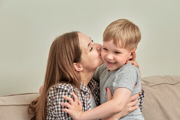 A happy family. A young mother hugged and kisses her son on the cheek.