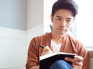 Young Asian man writing in a book