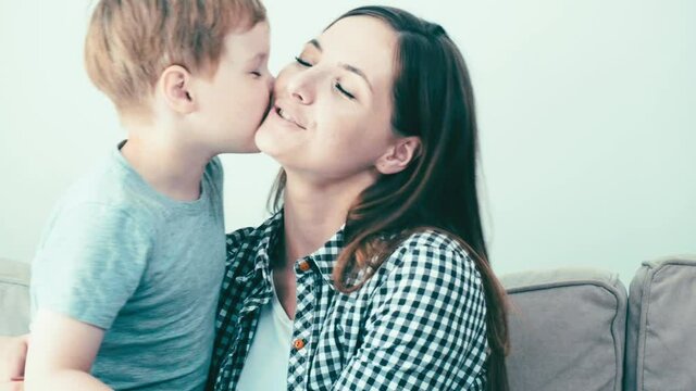 A little boy hugs and kisses his mother on the cheek. A loving, happy family. 4k