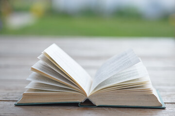An open old faded yellowed book on a green background. Minimal style, copy space. Side view