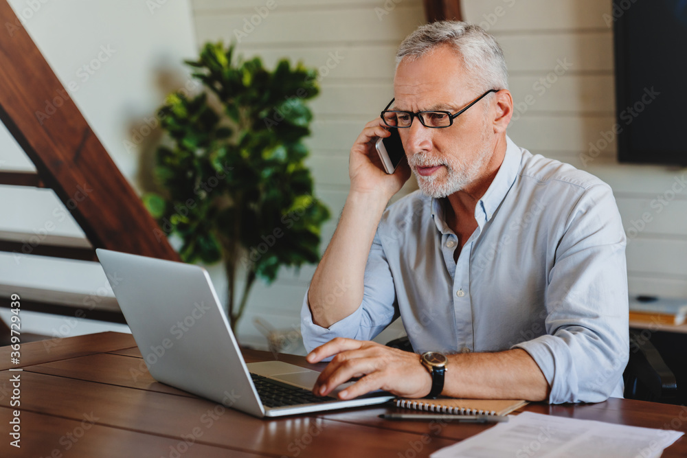 Wall mural remote working concept. mature man working from home on computer.