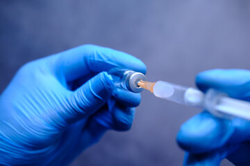 Doctor hands in medical gloves holds syringe and vaccine.