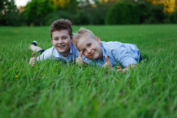 Naklejka na ściany i meble Two cheerful friends lying on green meadows in the park, after school.