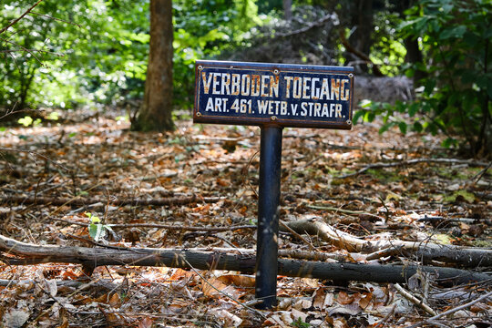 Dutch old blue rusty prohibited access sign in a wooded area. Criminal Code Act.461, Art.461. English translation:forbidden access, Article 461, Criminal Code